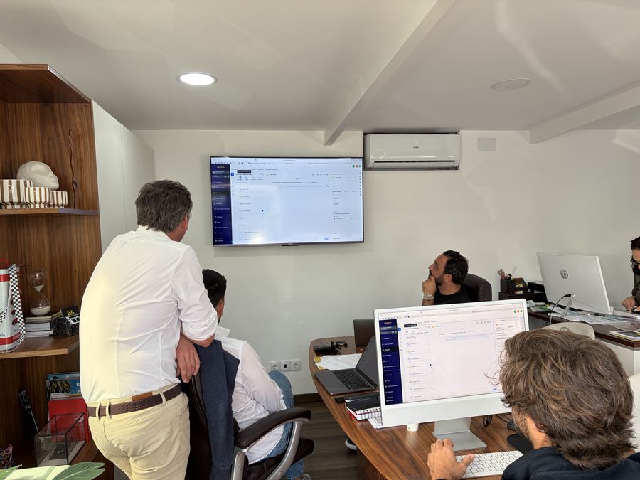 Reunião de trabalho num escritório, com a equipa à volta de um ecrã